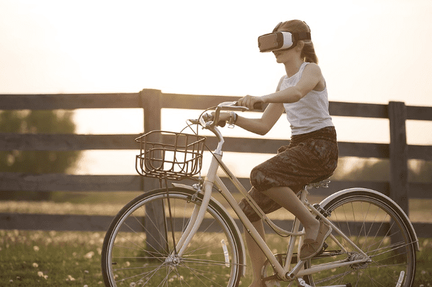 Girl riding bike with virtual reality goggles on